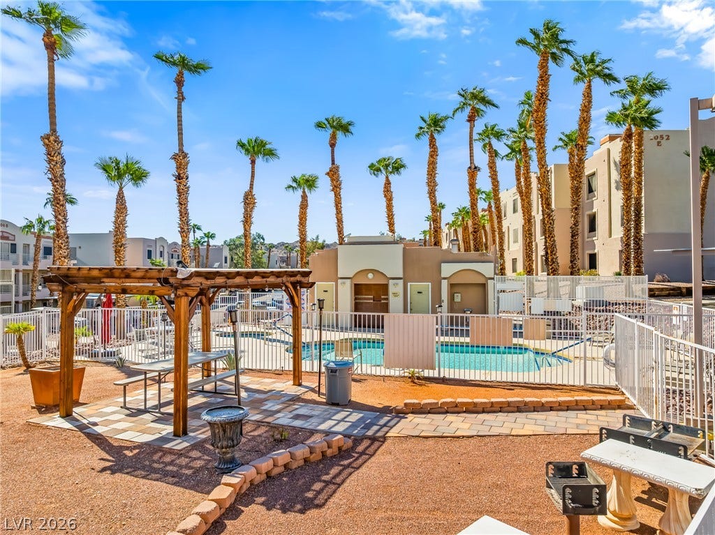 2036 Mesquite Lane, #303, Laughlin, NV 89029 Lush palm trees surround a community pool area with a shaded pergola and grill.