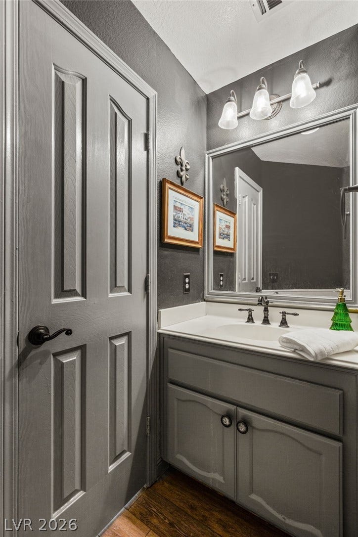3950 Candleglow Court, Las Vegas, NV 89147 A classic vanity setup and wood flooring define this elegant powder room.