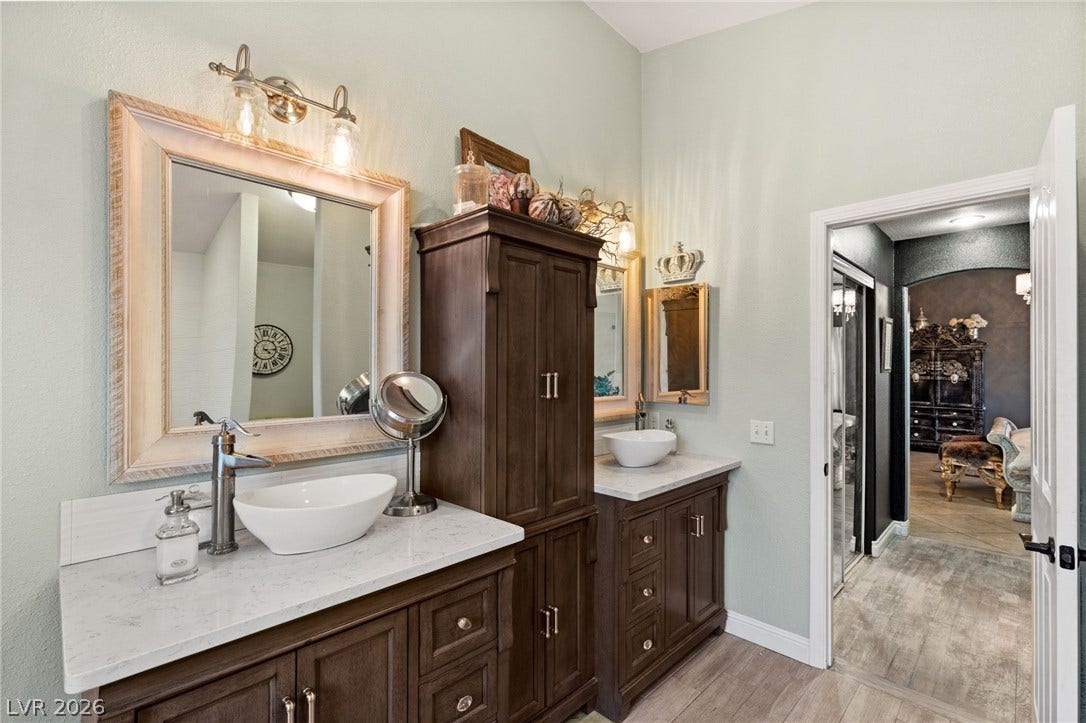 3950 Candleglow Court, Las Vegas, NV 89147 Double vanities with stone counters flank a central storage cabinet in this master bathroom.