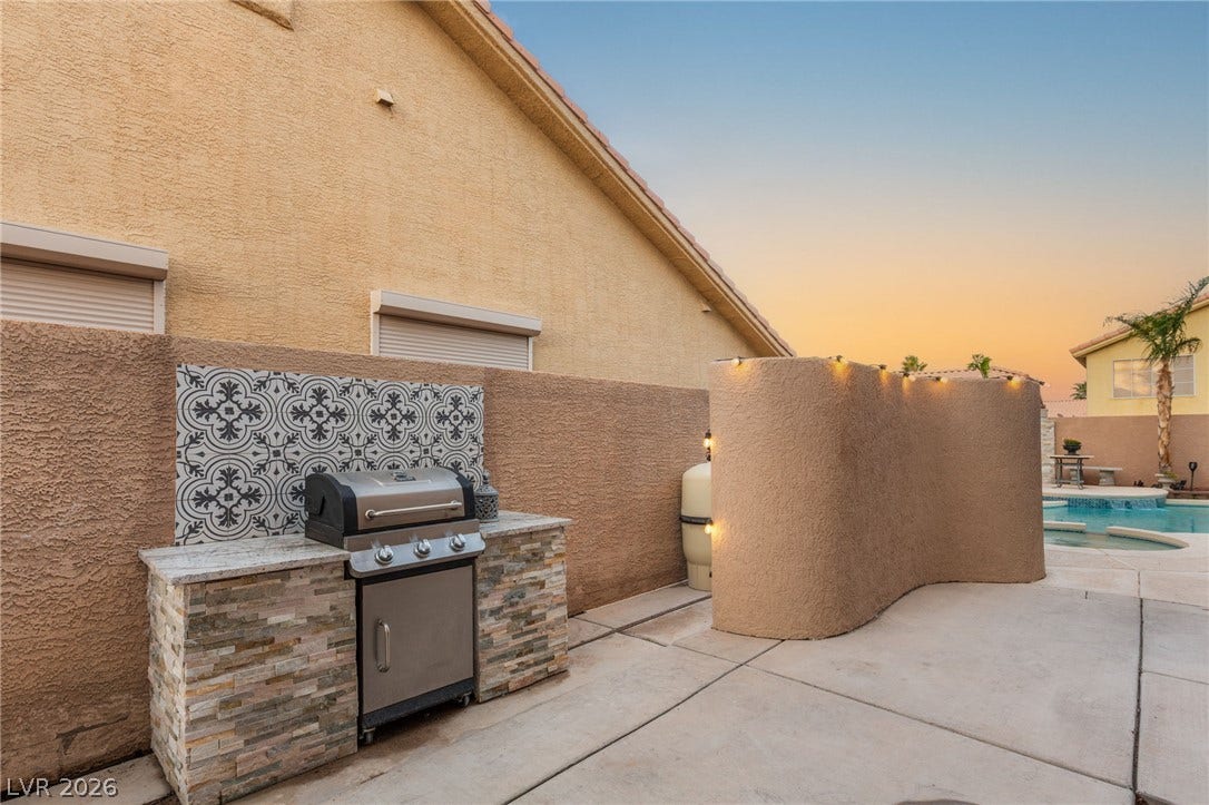 3950 Candleglow Court, Las Vegas, NV 89147 An inviting backyard patio features a built-in barbecue station adjacent to a sparkling pool.