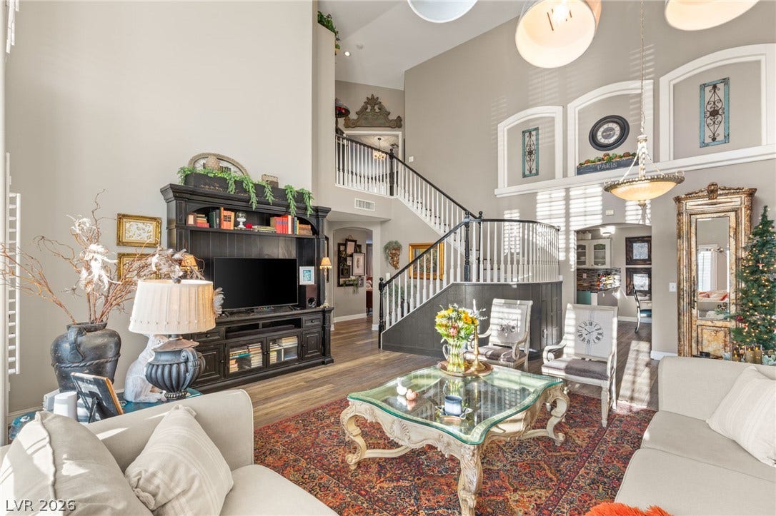 3950 Candleglow Court, Las Vegas, NV 89147 Dramatic vaulted ceilings and a sweeping staircase anchor this grand living space with rich hardwood flooring.