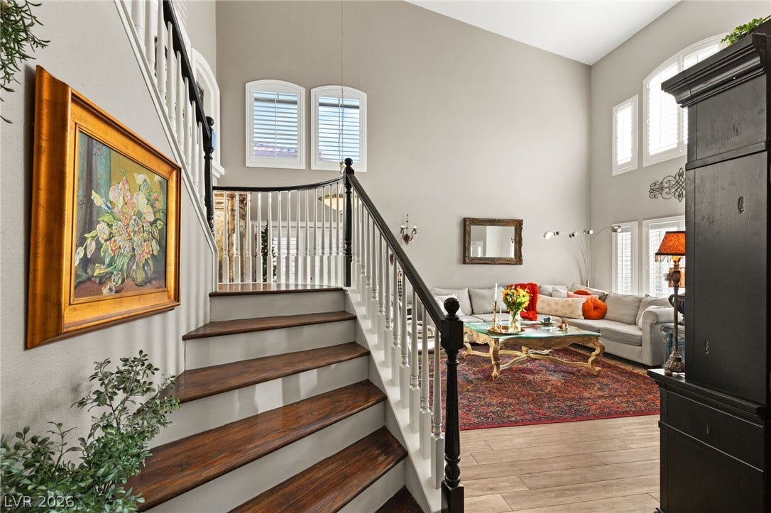 3950 Candleglow Court, Las Vegas, NV 89147 Towering ceilings and a grand wood staircase frame this open, light-filled living area.