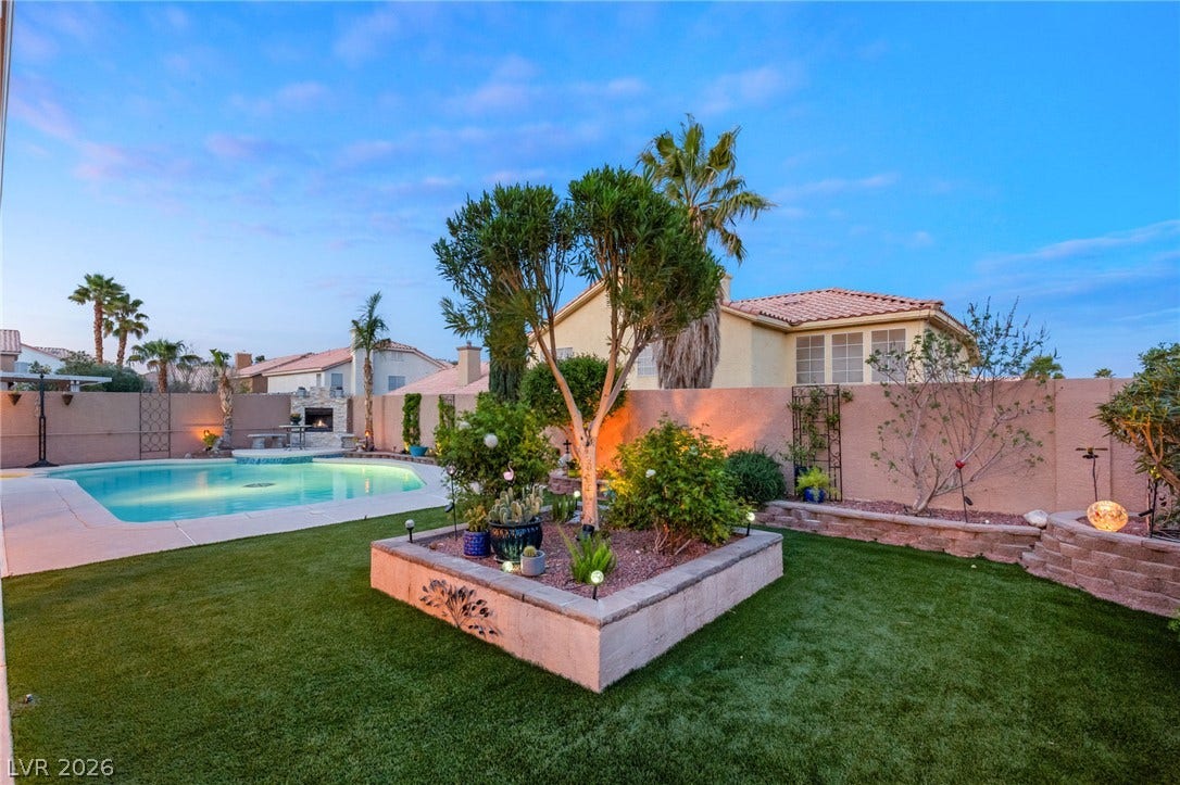 3950 Candleglow Court, Las Vegas, NV 89147 Lush manicured turf borders a sparkling swimming pool under an evening sky.