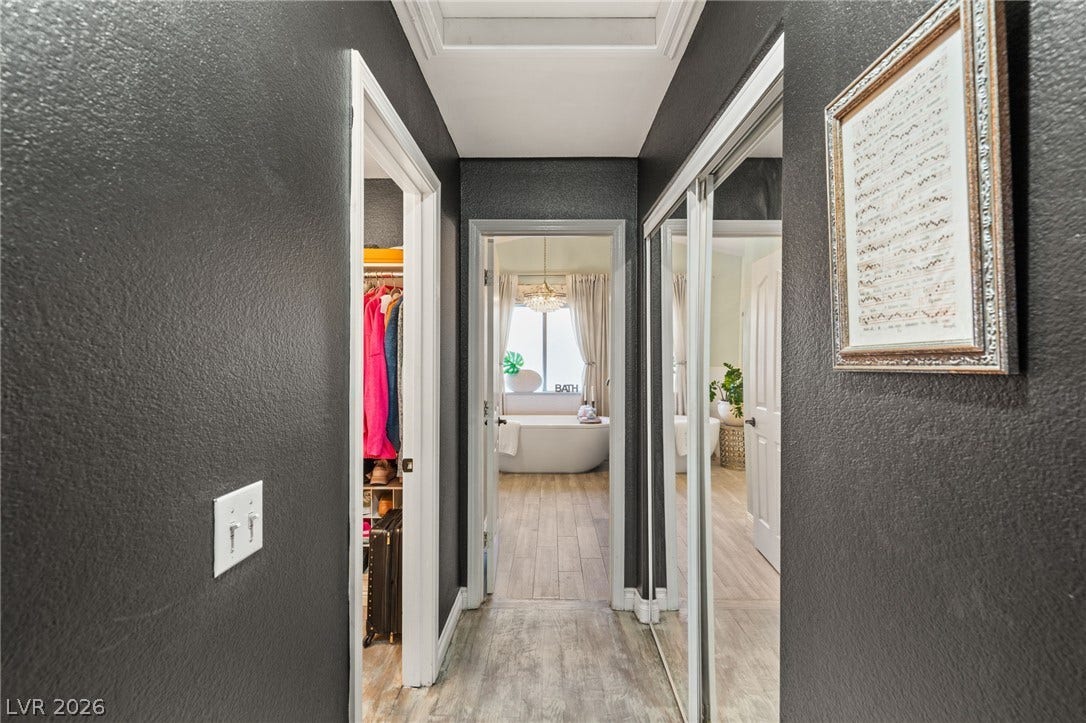 3950 Candleglow Court, Las Vegas, NV 89147 Dark textured walls line a hallway leading to a bright, modern bathroom.