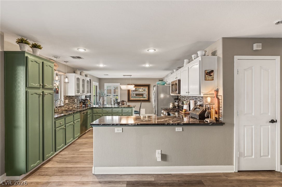 3950 Candleglow Court, Las Vegas, NV 89147 Polished stone countertops complement the dual-tone cabinetry and warm wood flooring.
