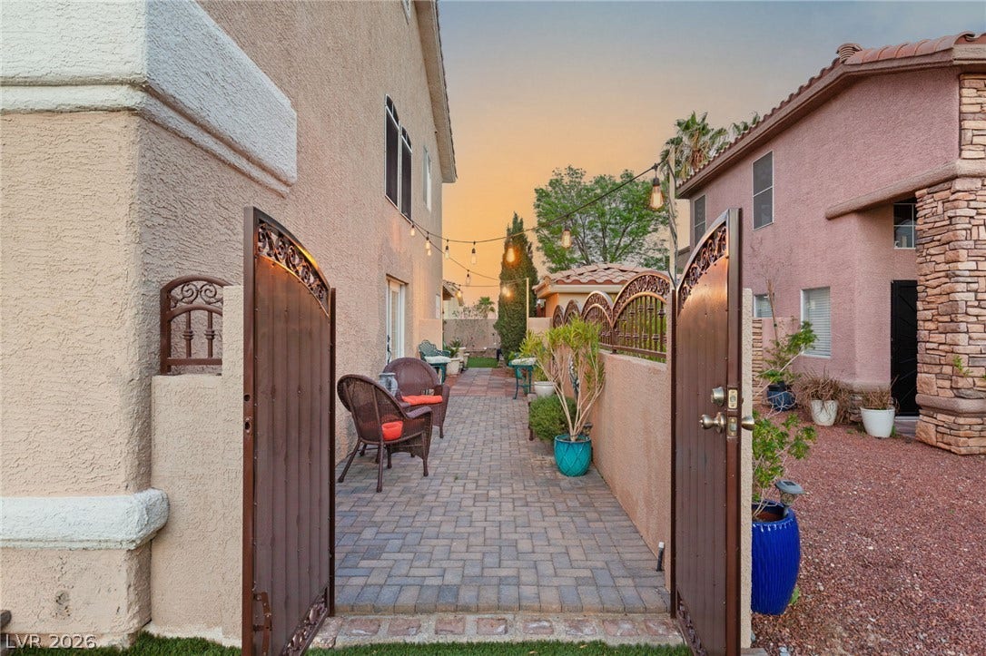 3950 Candleglow Court, Las Vegas, NV 89147 An inviting gated courtyard features paved walkways leading along the side of the stucco home.