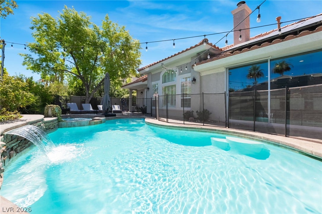 1892 Woodhaven Drive, Henderson, NV 89074 An inviting backyard oasis offers a sparkling pool with a cascading waterfall feature and a tranquil spa, perfect for relaxation.