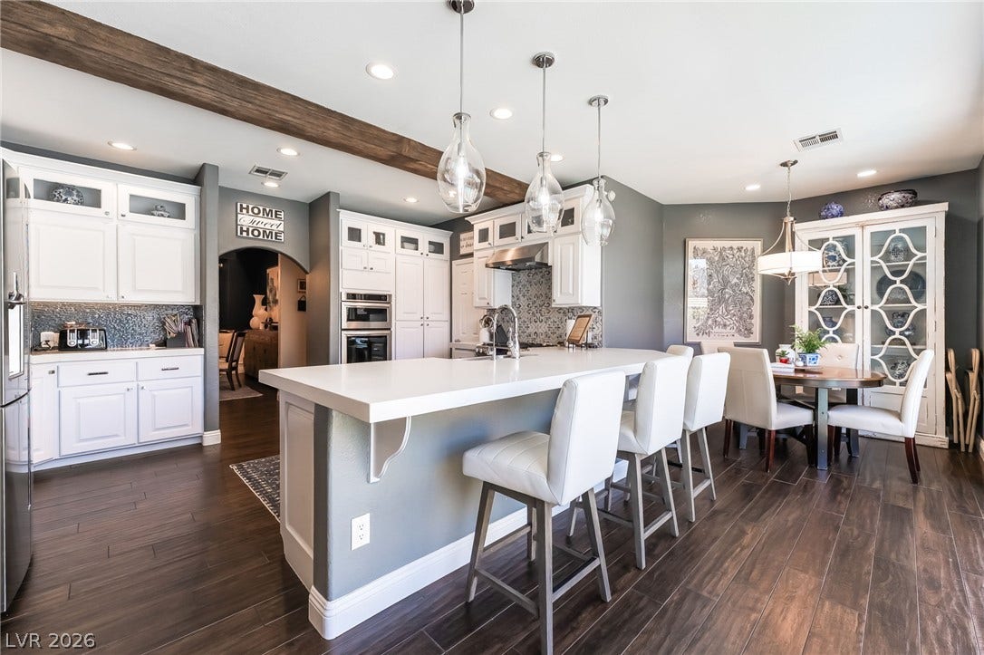 1892 Woodhaven Drive, Henderson, NV 89074 A well-appointed kitchen boasts white cabinetry, a spacious island, and wood-look tile flooring.