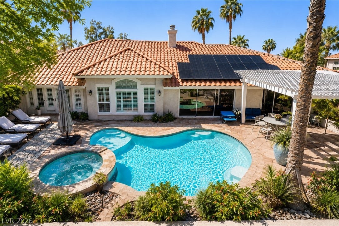 1892 Woodhaven Drive, Henderson, NV 89074 An inviting backyard oasis features a free-form pool, integrated spa, and spacious patio under a pergola, ideal for leisure. Photo has safety pool fence removed.