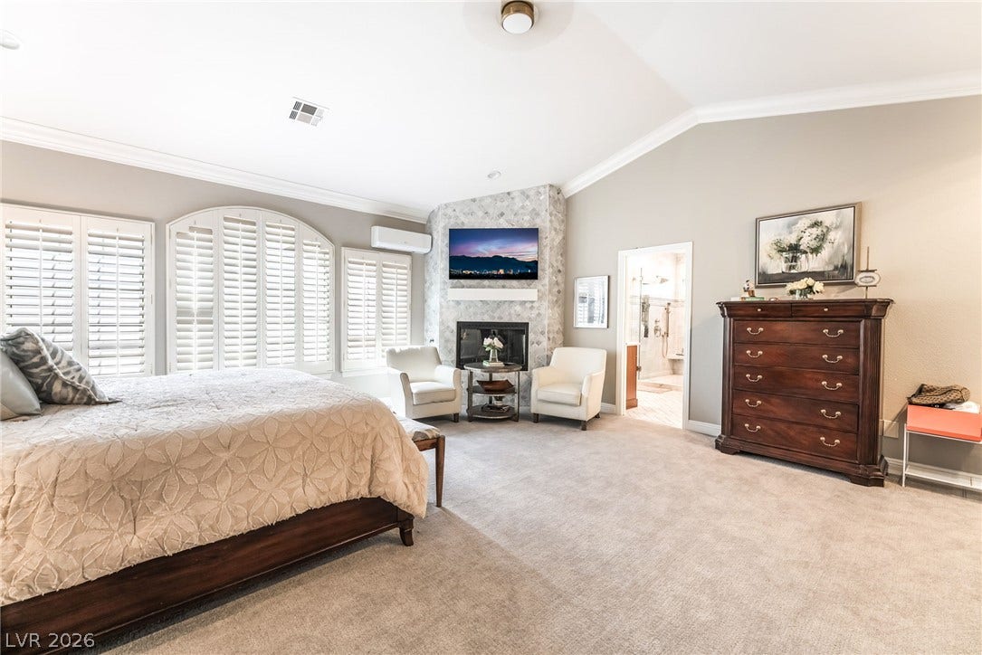 1892 Woodhaven Drive, Henderson, NV 89074 Relax in this primary bedroom featuring a corner fireplace and a wall of arched windows.