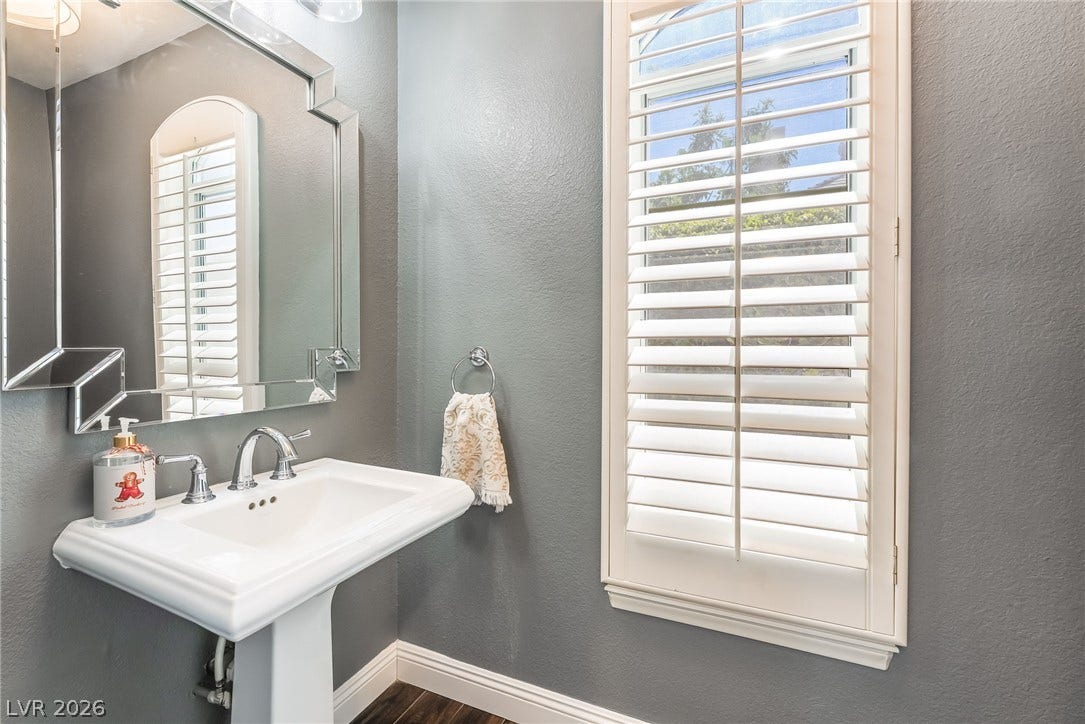 1892 Woodhaven Drive, Henderson, NV 89074 Refined pedestal sink with a framed mirror and plantation shutters complete this well-appointed bathroom.