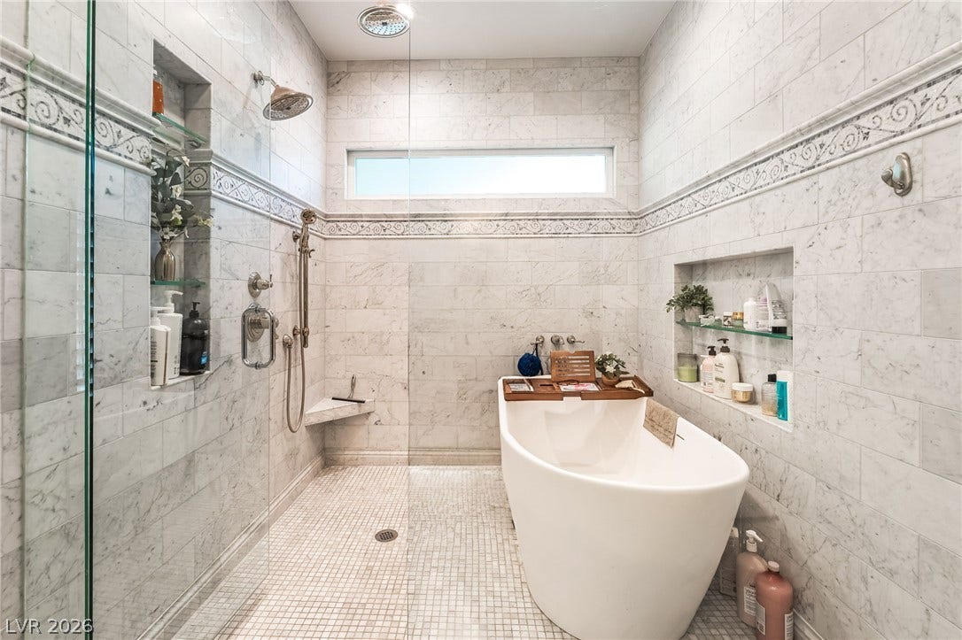 1892 Woodhaven Drive, Henderson, NV 89074 Marble-clad walls and a spacious shower elevate this primary bath to a personal spa retreat.