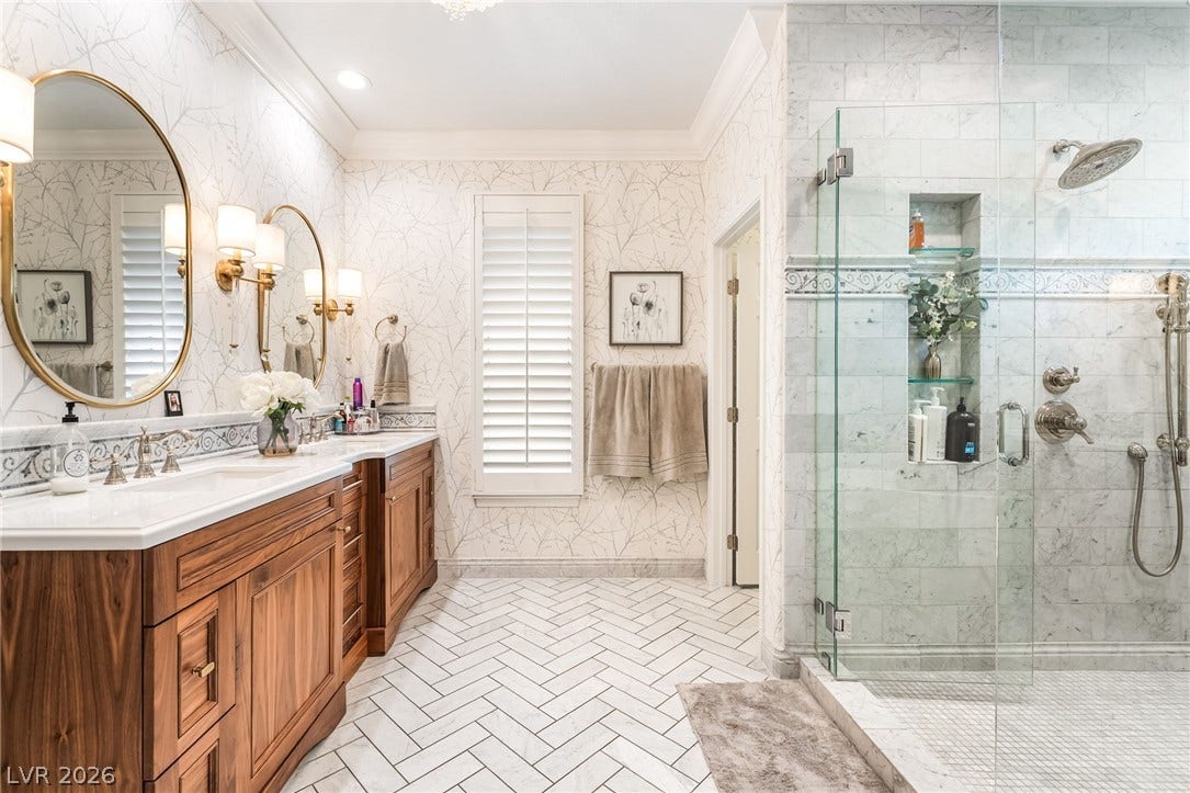 1892 Woodhaven Drive, Henderson, NV 89074 Marble tile flooring and a glass-enclosed shower complement the rich wood double vanity in this primary bathroom.