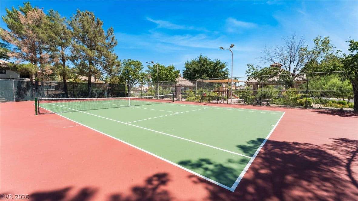 1892 Woodhaven Drive, Henderson, NV 89074 Green and red tennis court with overhead lighting set against a backdrop of mature trees.