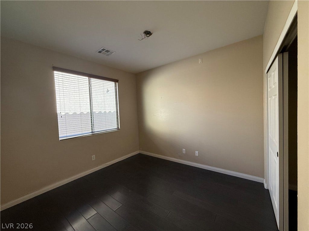 4327 Oasis Hill Avenue, North Las Vegas, NV 89085 Rich dark wood flooring anchors this versatile bedroom space featuring a wide window.