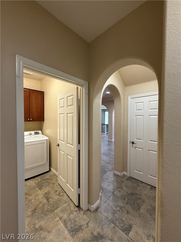 4327 Oasis Hill Avenue, North Las Vegas, NV 89085 Graceful arched doorways frame the view through this tiled hallway toward the dedicated laundry area.