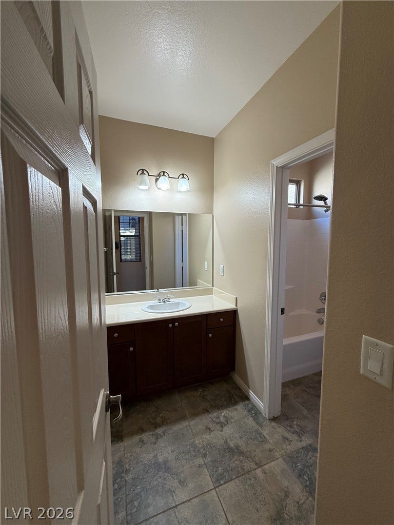 4327 Oasis Hill Avenue, North Las Vegas, NV 89085 Tile flooring and a dark wood vanity anchor this classic bathroom layout.