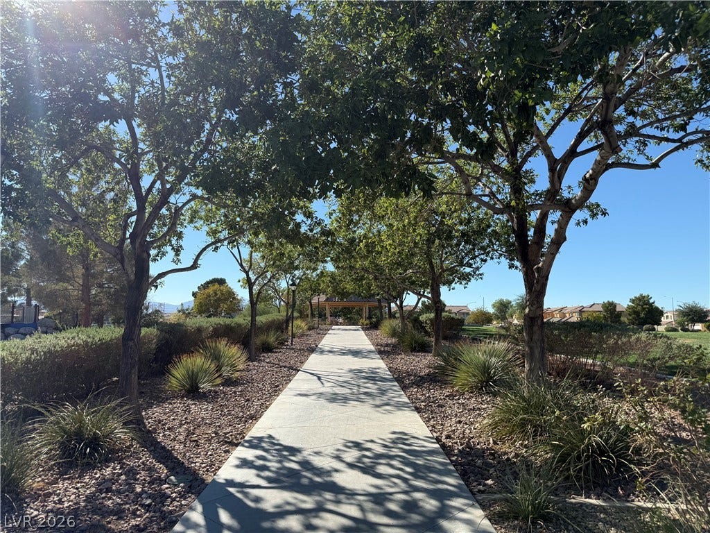 4327 Oasis Hill Avenue, North Las Vegas, NV 89085 Mature trees shade a paved walkway leading toward a community gazebo.