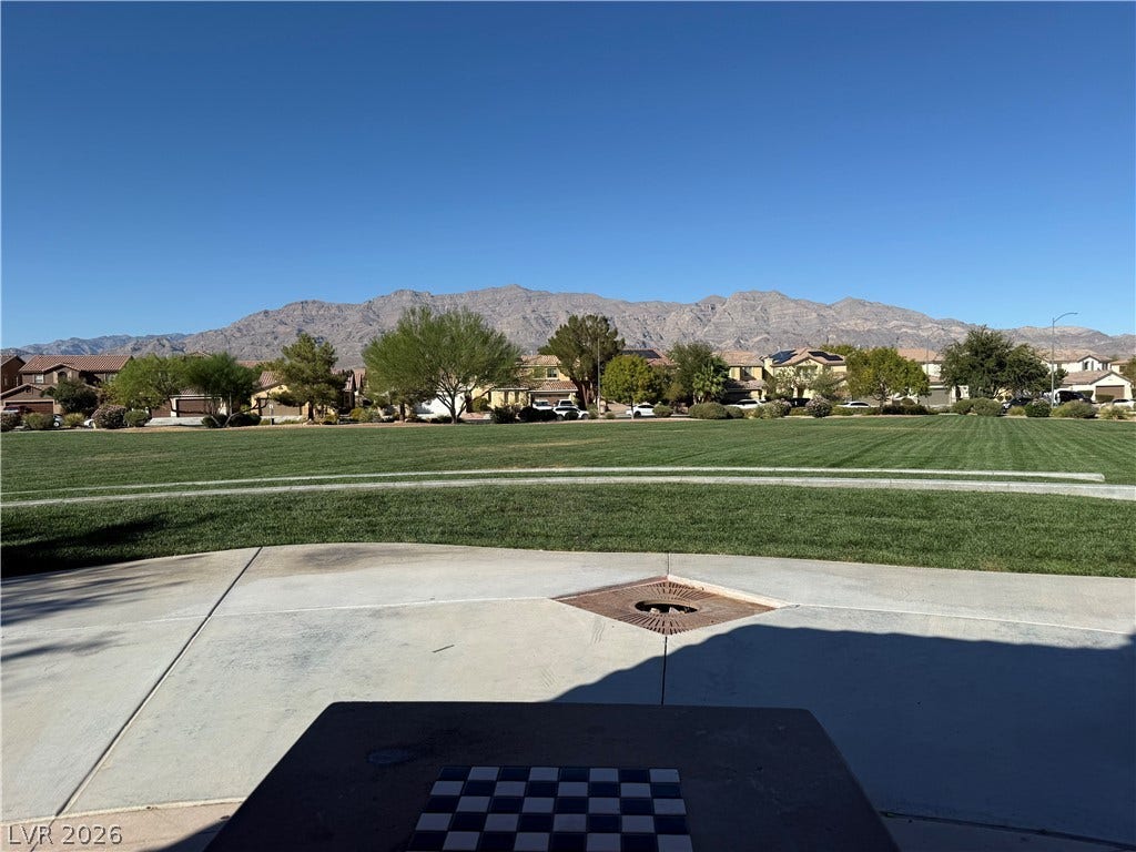 4327 Oasis Hill Avenue, North Las Vegas, NV 89085 A spacious grassy park area rests against a dramatic mountain backdrop under clear blue skies.