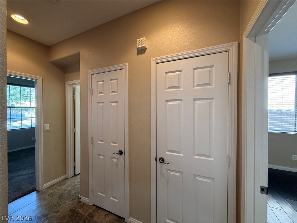 4327 Oasis Hill Avenue, North Las Vegas, NV 89085 Six-panel doors and recessed lighting line a central hallway with tile flooring.