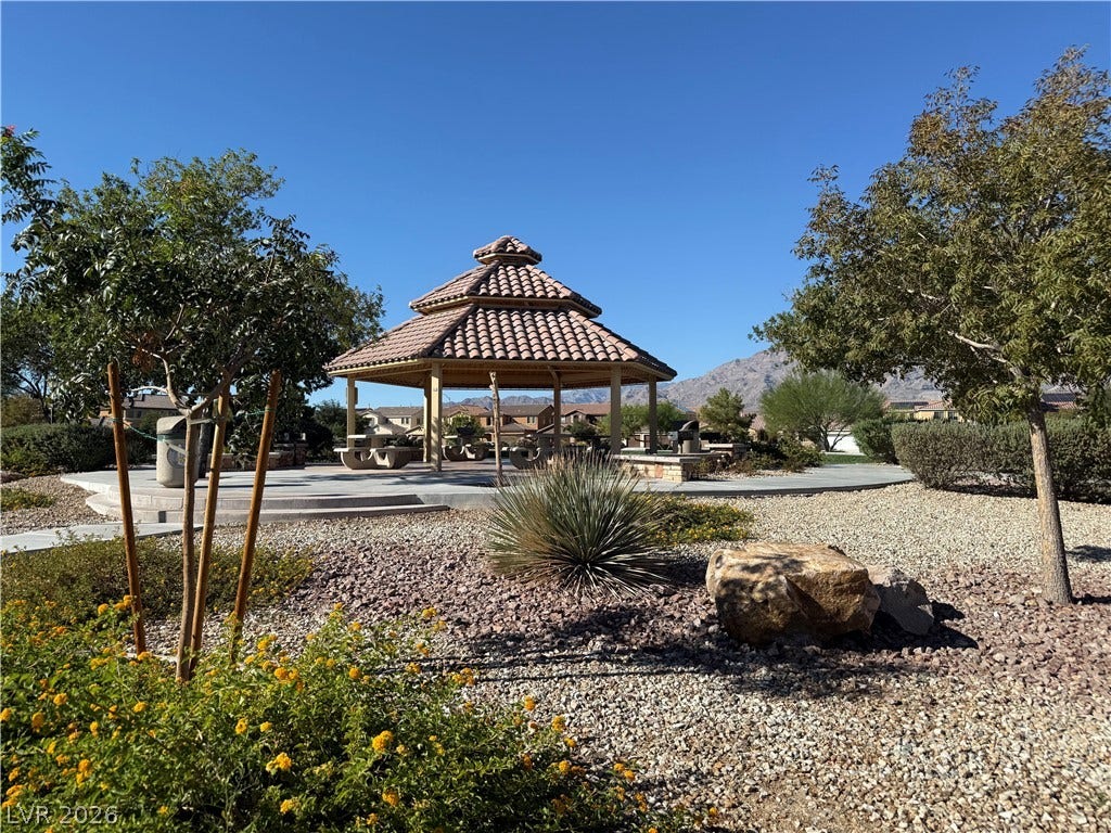 4327 Oasis Hill Avenue, North Las Vegas, NV 89085 An inviting tiled pavilion stands amidst desert landscaping with mountain backdrops under clear skies.