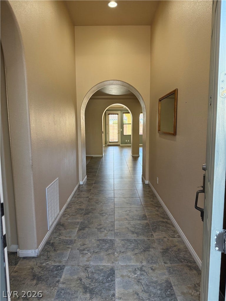4327 Oasis Hill Avenue, North Las Vegas, NV 89085 Dramatic arched doorways frame the view down a long tiled hallway under soaring ceilings.