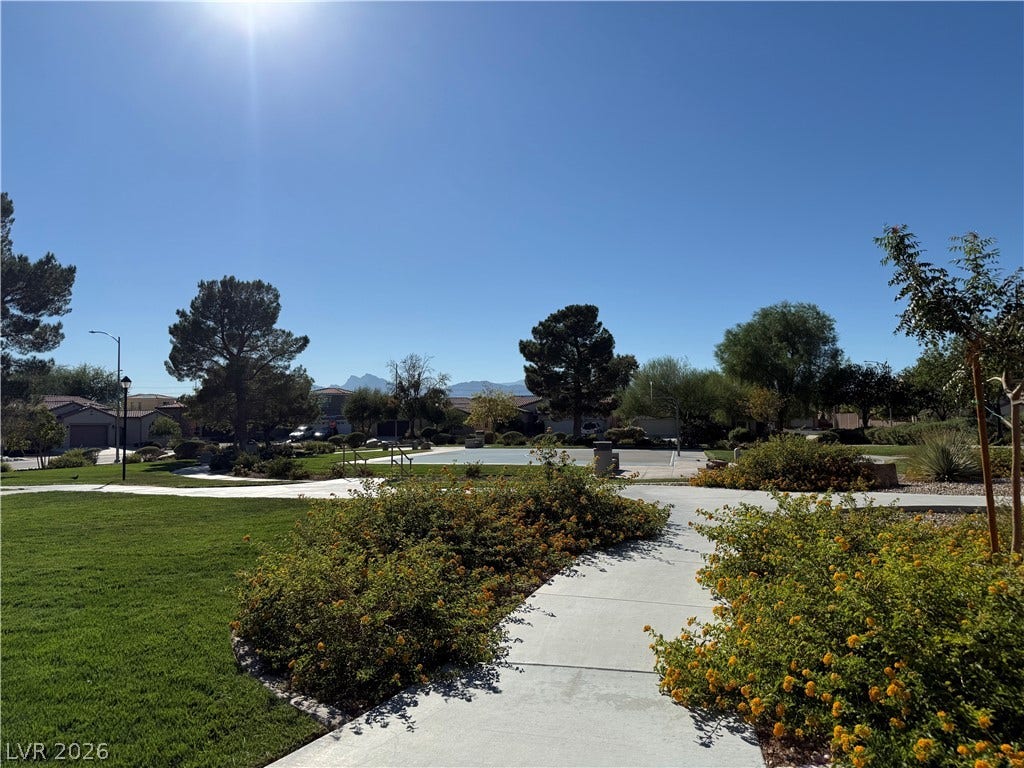 4327 Oasis Hill Avenue, North Las Vegas, NV 89085 Paved pathways wind through beautifully landscaped green spaces under a clear blue sky.