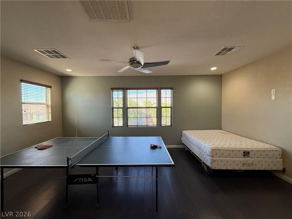 4327 Oasis Hill Avenue, North Las Vegas, NV 89085 Rich dark wood flooring anchors this versatile space featuring dual windows for natural light.