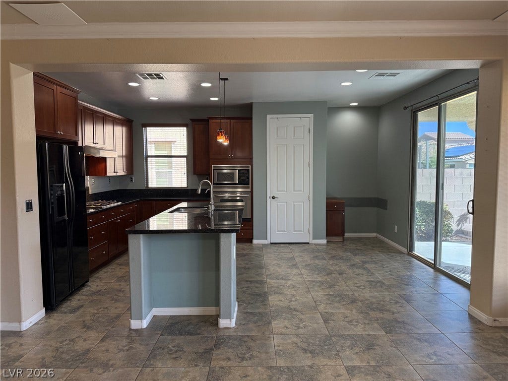 4327 Oasis Hill Avenue, North Las Vegas, NV 89085 Granite counters and rich wood cabinetry anchor this spacious tiled kitchen with an island.