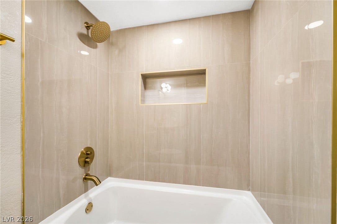 601 Cabrillo Circle, #431, Henderson, NV 89015 Floor-to-ceiling tiling and modern brass hardware elevate this integrated shower and tub enclosure.