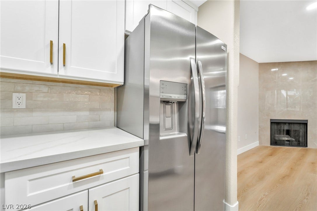 601 Cabrillo Circle, #431, Henderson, NV 89015 Gleaming cabinetry and stone countertops flow seamlessly toward a cozy modern living room fireplace.