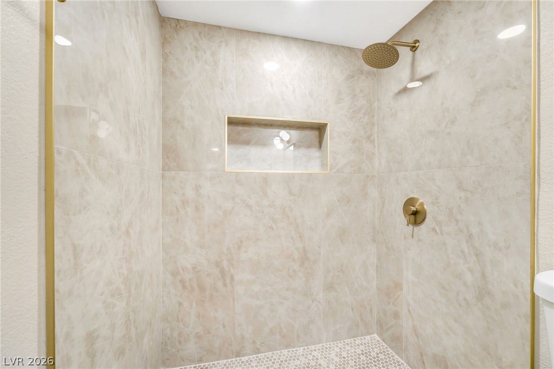 601 Cabrillo Circle, #431, Henderson, NV 89015 Elegant tile surrounds a modern walk-in shower accented with gold fixtures and a recessed niche.