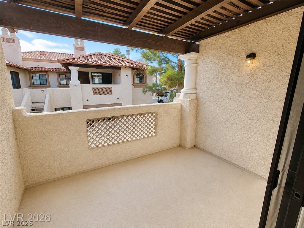 1417 Santa Margarita Street, #G, Las Vegas, NV 89146 A private covered balcony of primary bedroom features textured walls and a slatted wood overhead trellis.