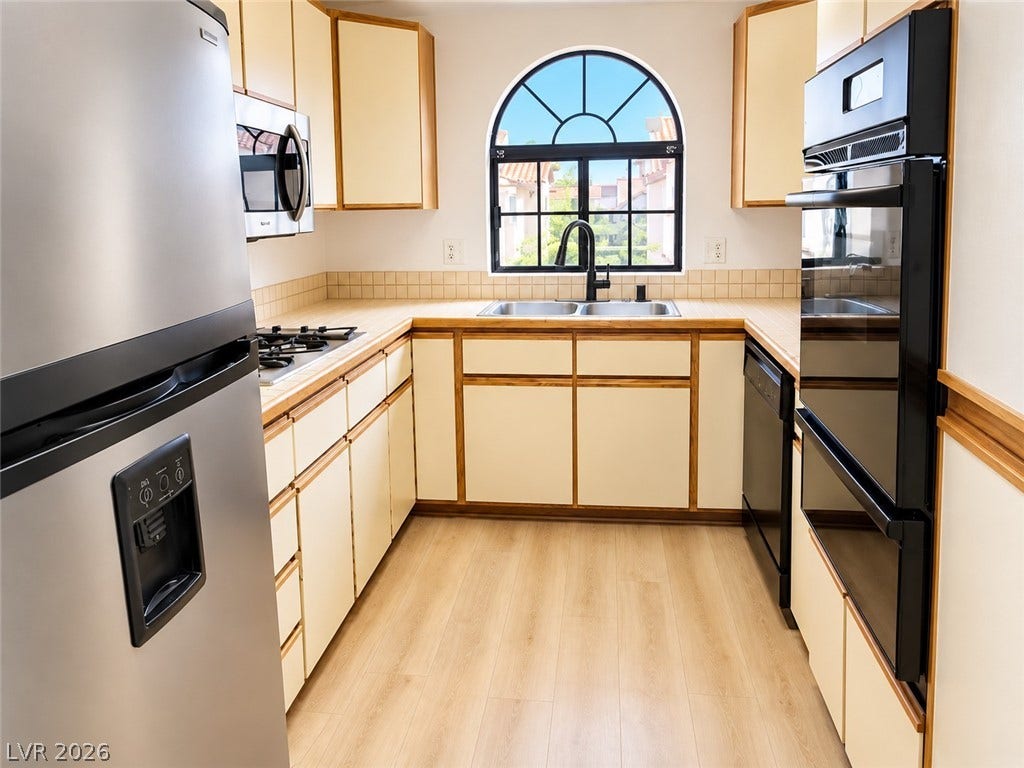 1417 Santa Margarita Street, #G, Las Vegas, NV 89146 An arched window floods this functional kitchen with natural light over expansive tile countertops.