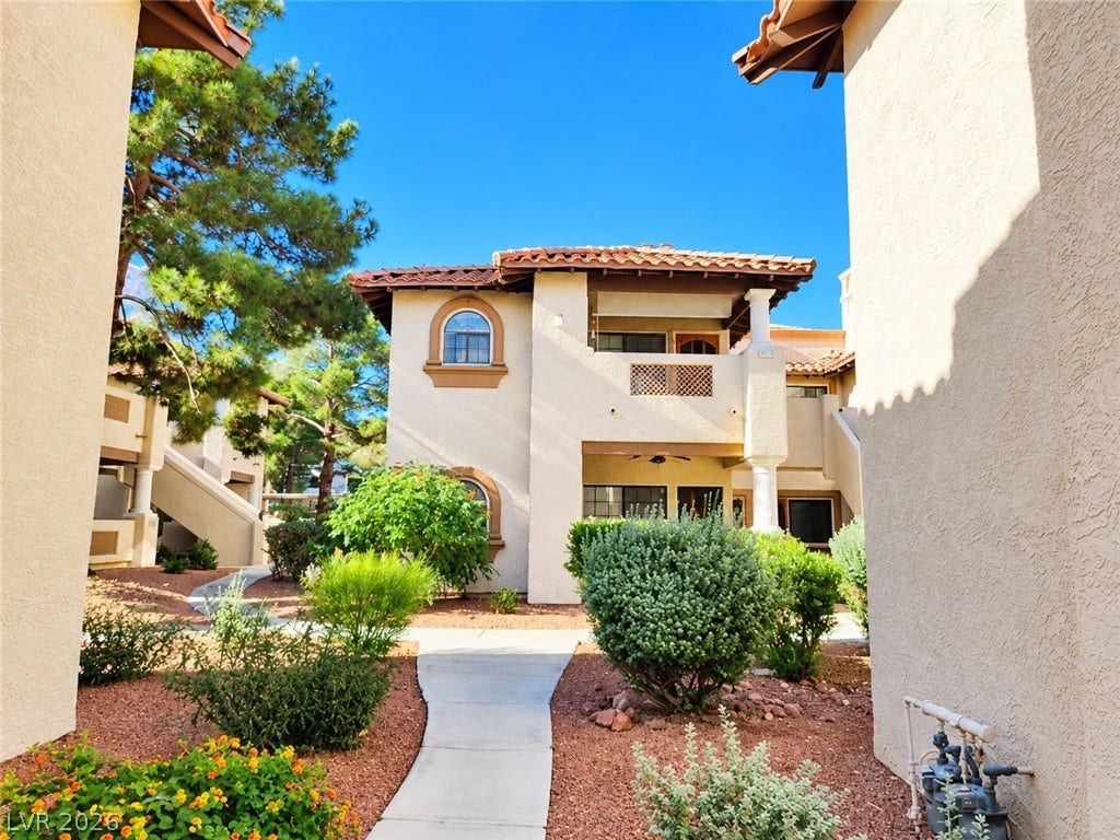 1417 Santa Margarita Street, #G, Las Vegas, NV 89146 Manicured pathways wind through lush green landscaping toward Mediterranean-inspired exterior architecture.