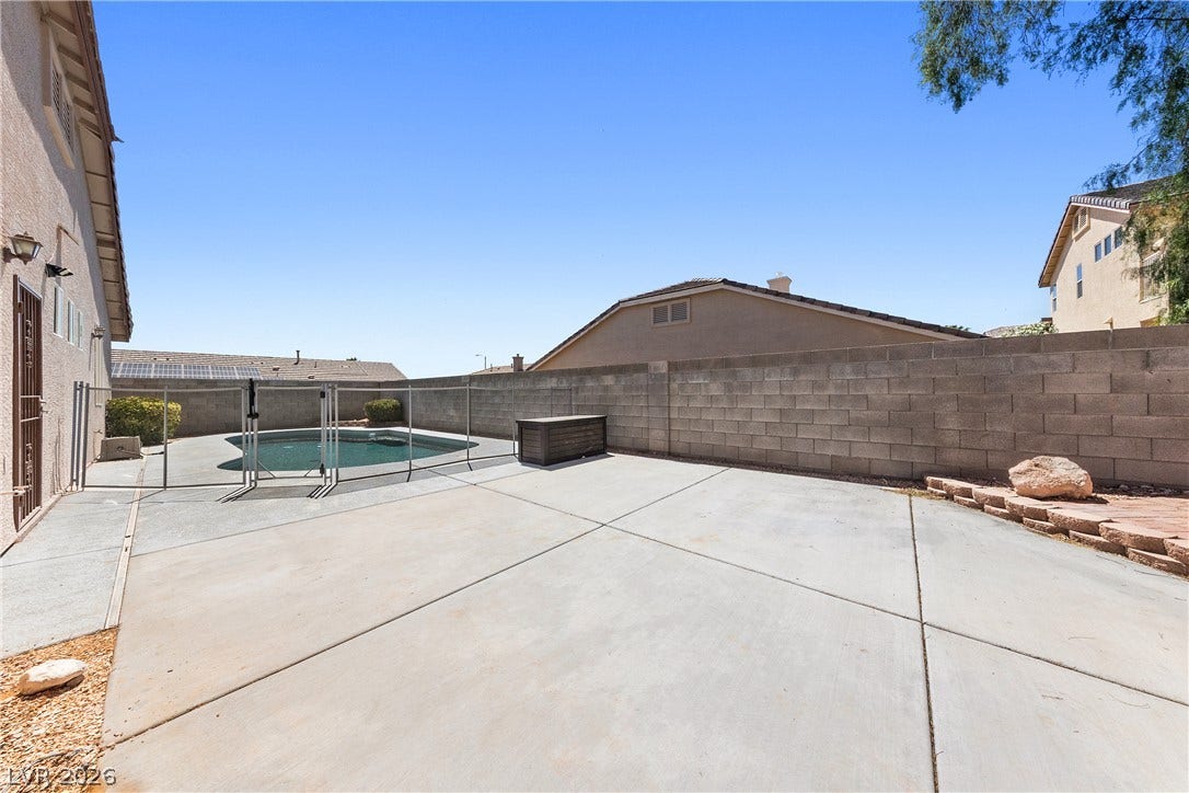 9613 Cherry Canyon Avenue, Las Vegas, NV 89129 A spacious concrete patio borders a fenced pool under clear desert skies.