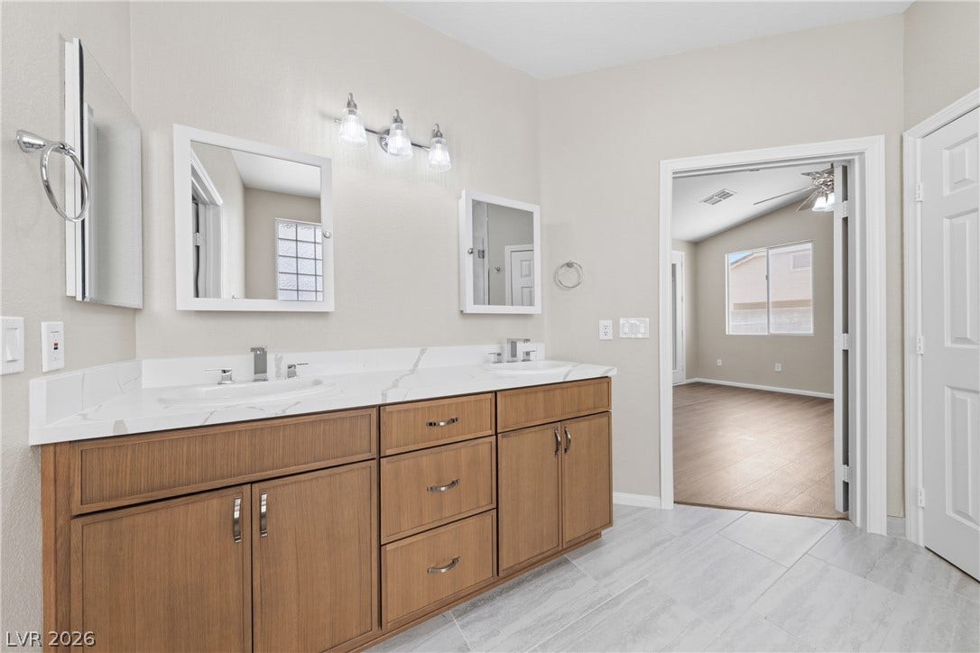 9613 Cherry Canyon Avenue, Las Vegas, NV 89129 A spacious double vanity features sleek stone countertops and classic wood cabinetry.