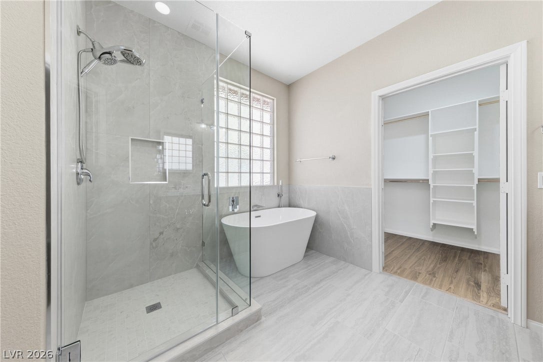 9613 Cherry Canyon Avenue, Las Vegas, NV 89129 Elegant tile floors anchor a bathroom complete with a glass-enclosed shower and soaking tub.