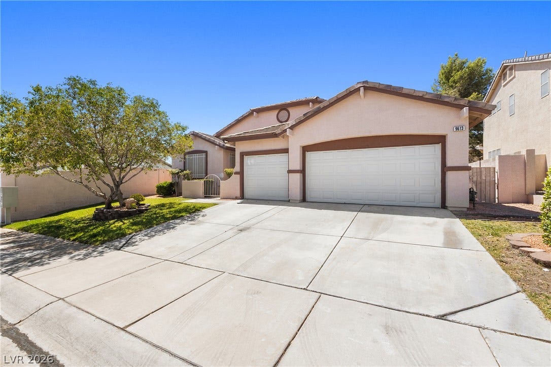 9613 Cherry Canyon Avenue, Las Vegas, NV 89129 An expansive concrete driveway leads to a three-car garage set against a stucco exterior.