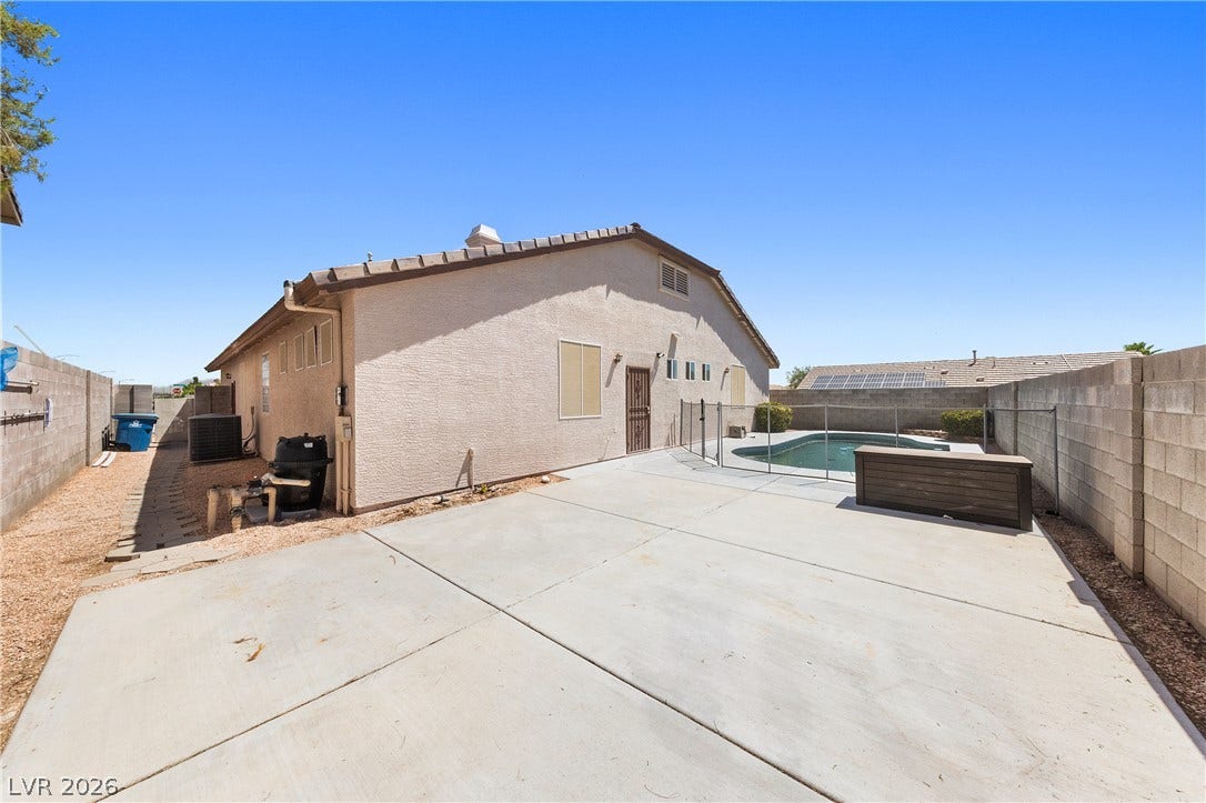 9613 Cherry Canyon Avenue, Las Vegas, NV 89129 A spacious concrete patio borders the fenced in-ground pool under clear blue skies.