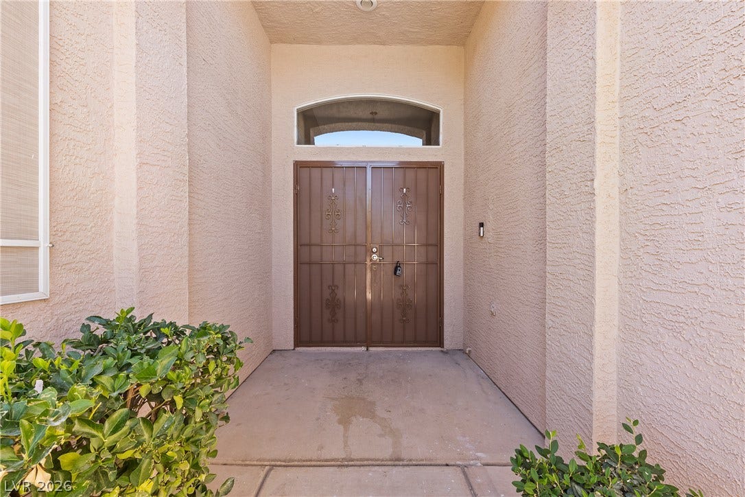 9613 Cherry Canyon Avenue, Las Vegas, NV 89129 Double doors with ornamental security gates welcome guests under a high recessed entryway.