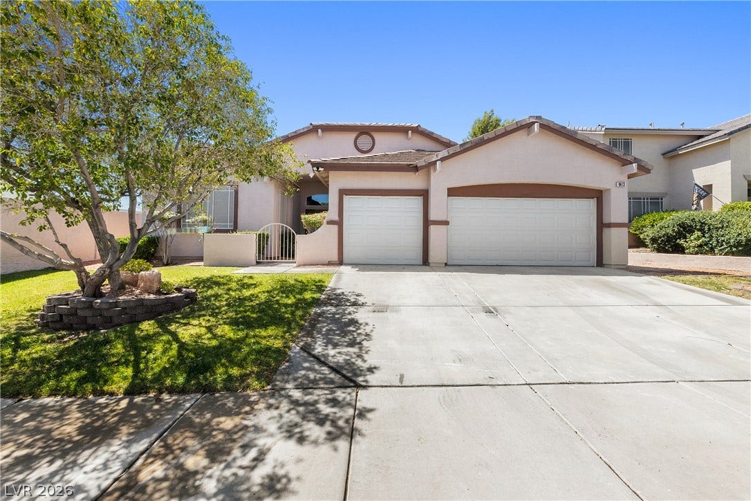 9613 Cherry Canyon Avenue, Las Vegas, NV 89129 An expansive concrete driveway leads to a classic tile-roof residence with a multi-car garage.