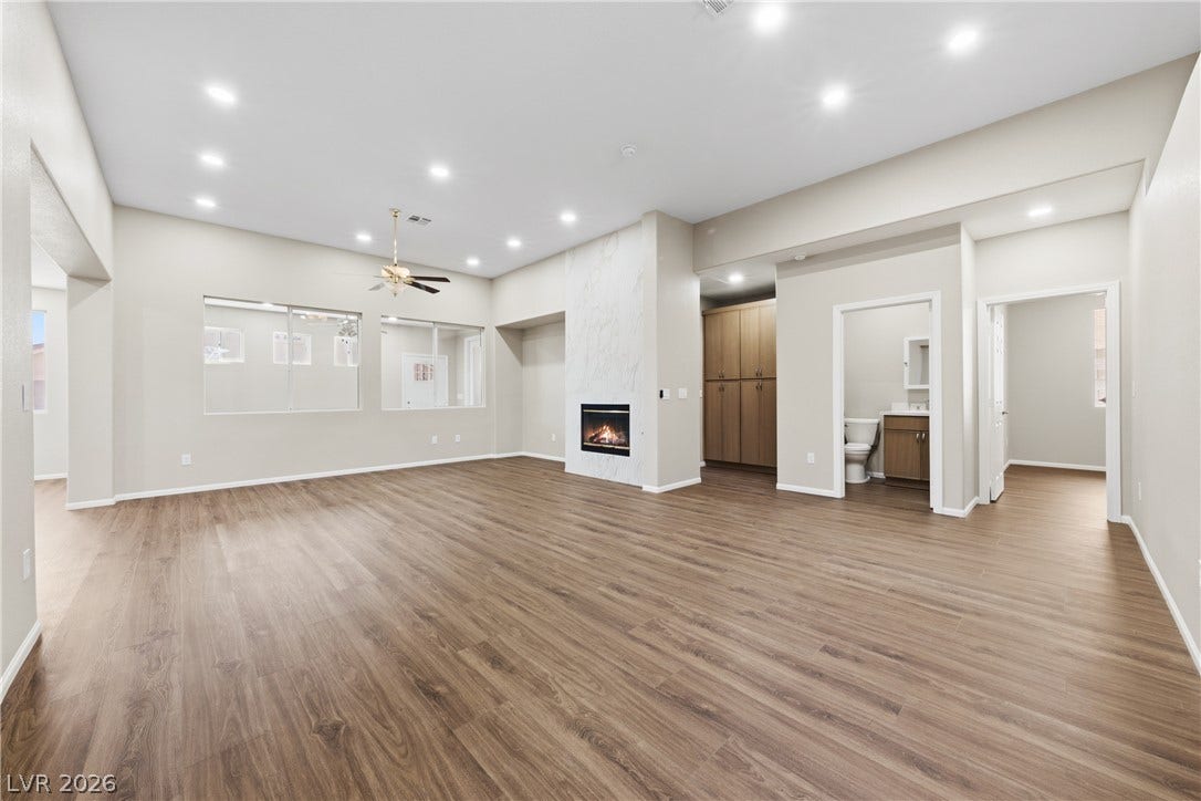 9613 Cherry Canyon Avenue, Las Vegas, NV 89129 Rich wood-look flooring and a modern fireplace elevate this airy living space.