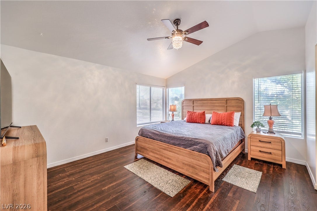 Rich hardwood floors contrast with clean walls and high vaulted ceilings in this bedroom.