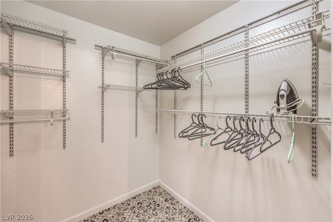 Adjustable wire shelving maximizes storage options above pattern tile flooring in this walk-in closet.