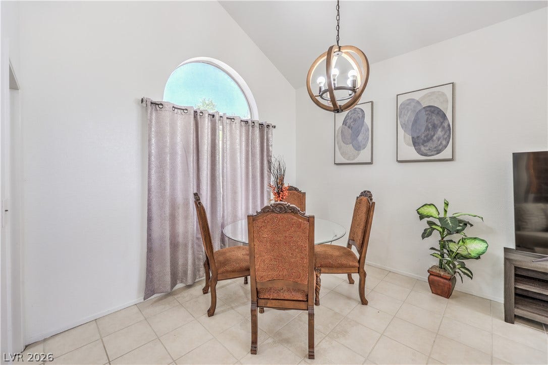 Vaulted ceilings and tile flooring create an airy dining space lit by an arched window.