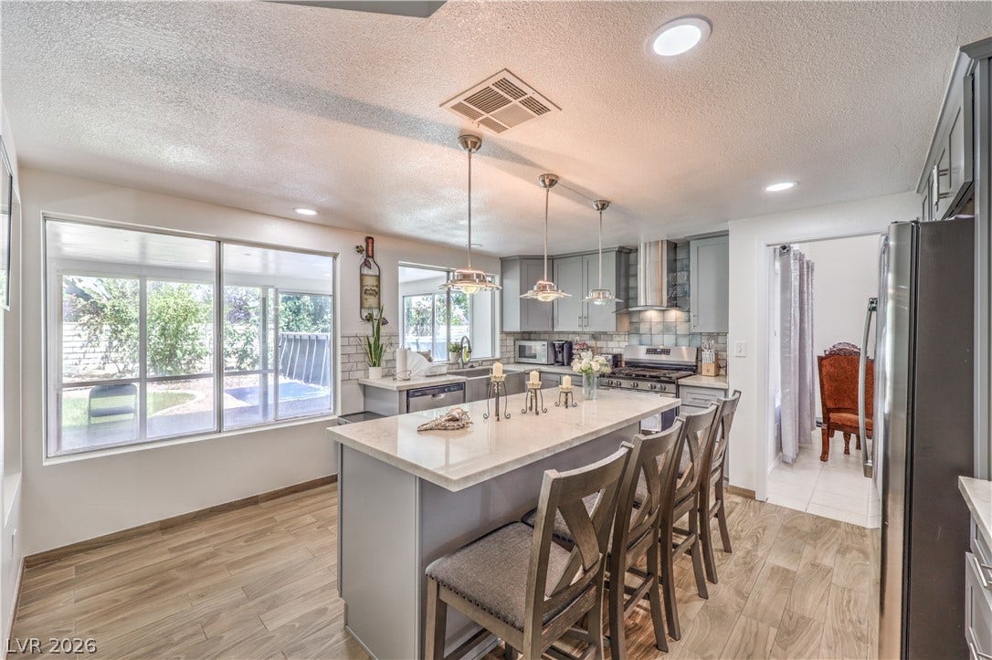 Gleaming stone countertops and wood-look flooring define this modern, sunlit culinary space.