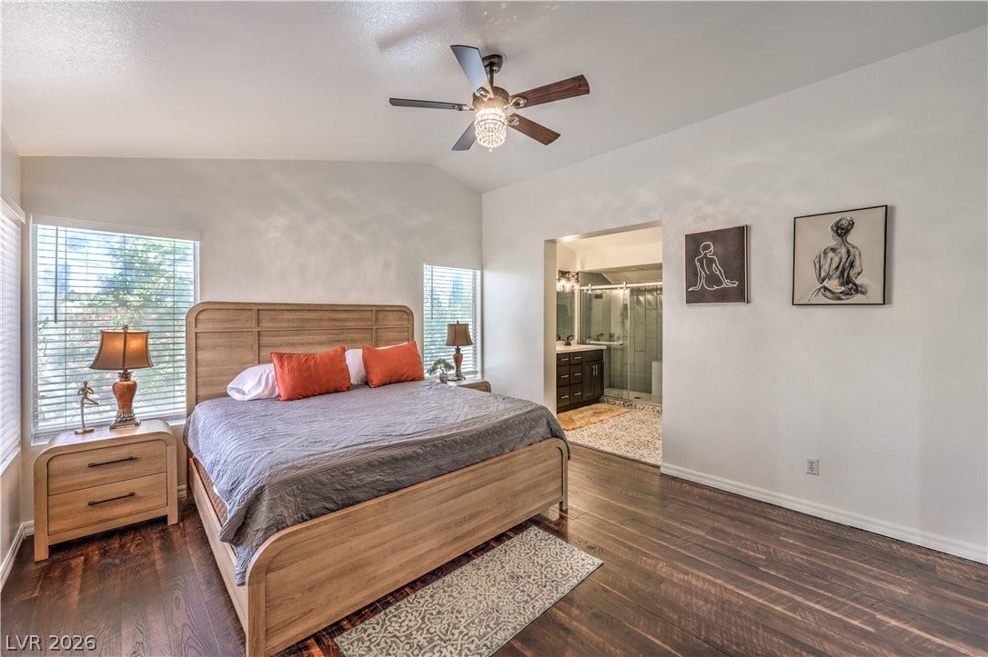 Rich hardwood flooring complements the vaulted ceiling of this primary bedroom suite.