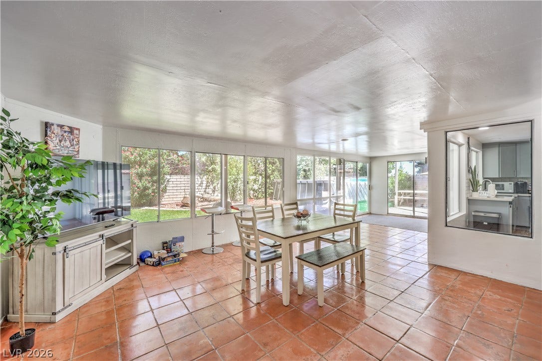 Warm tile flooring runs throughout this versatile dining area lined with wall-to-wall windows.