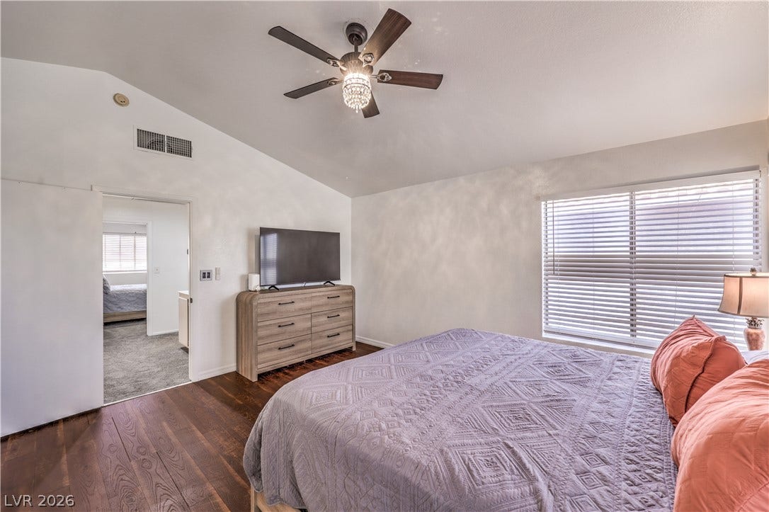 Rich hardwood flooring anchors this cozy bedroom under a vaulted ceiling line.